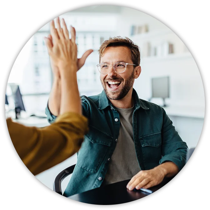Smiling man giving a high five to a colleague in a bright modern office.
